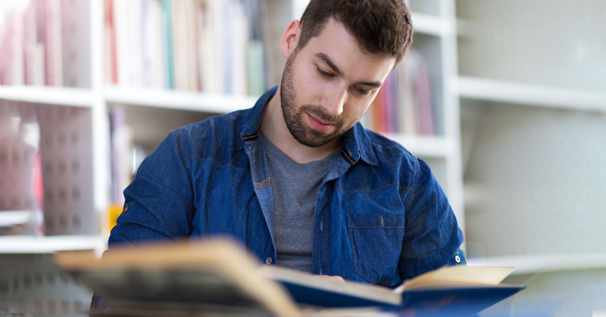 A man reading a book in a library.