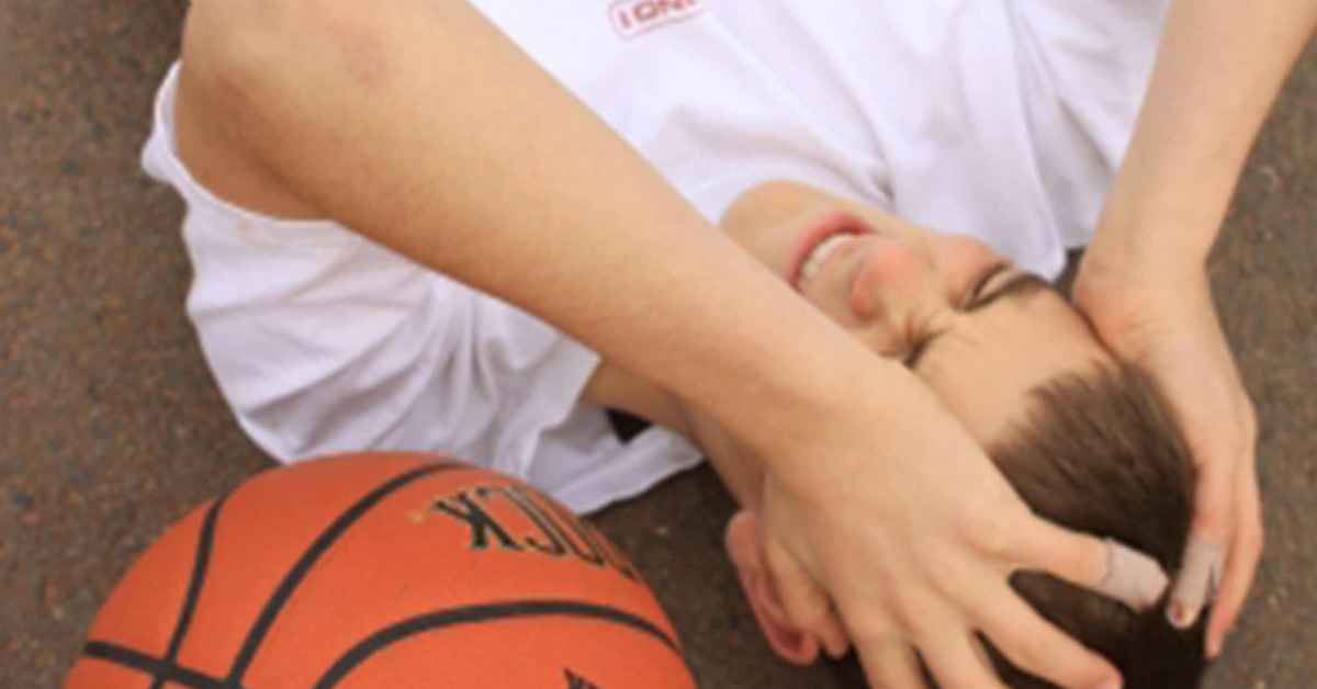 A young boy laying on the ground with a basketball ball.