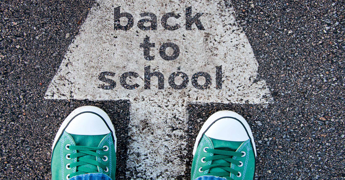 A pair of green sneakers standing next to a back to school sign.