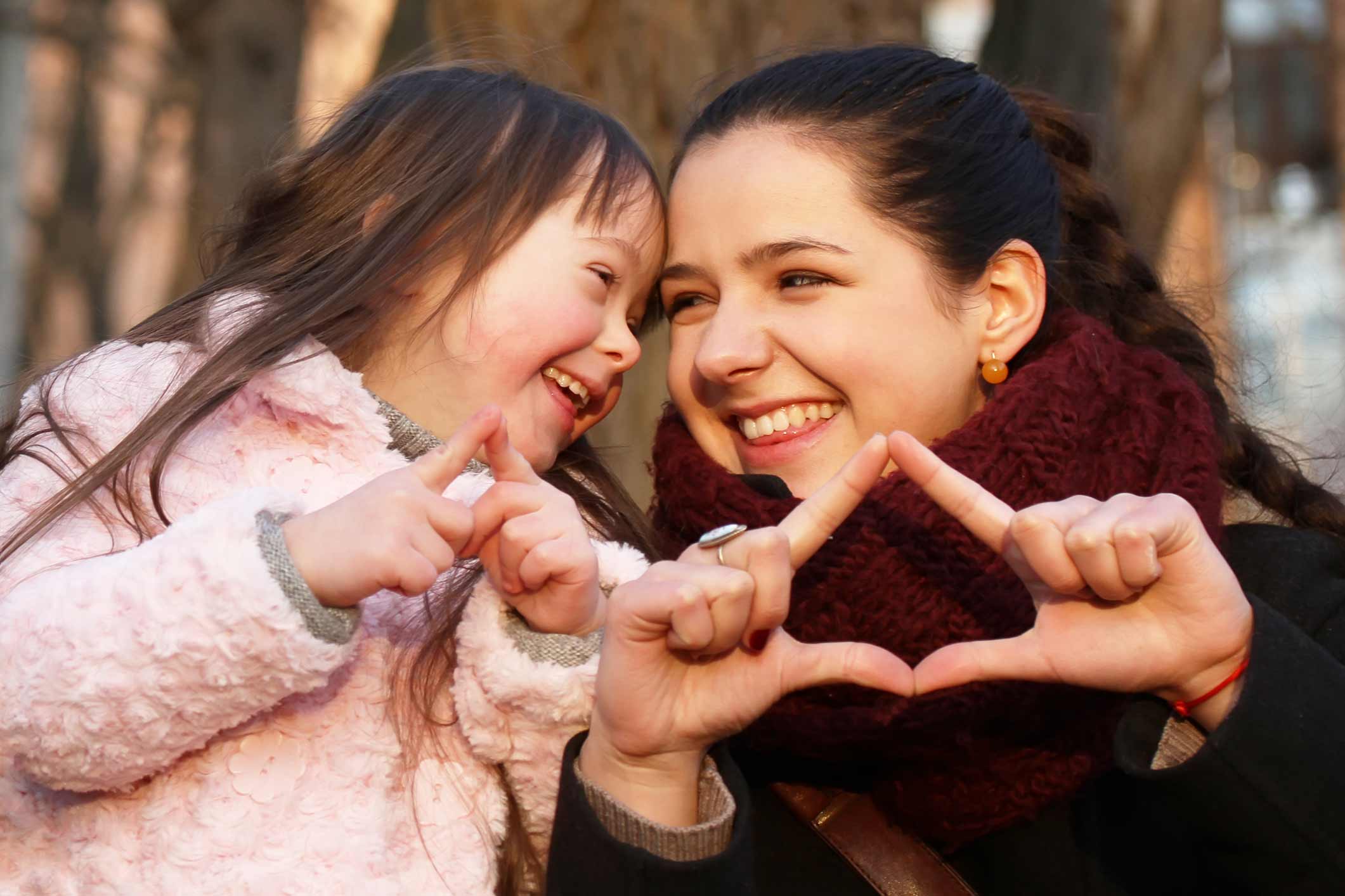 A mother and daughter making a heart shape with their hands.