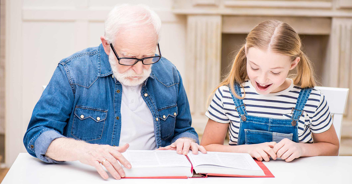 An older man and a young girl reading a book.