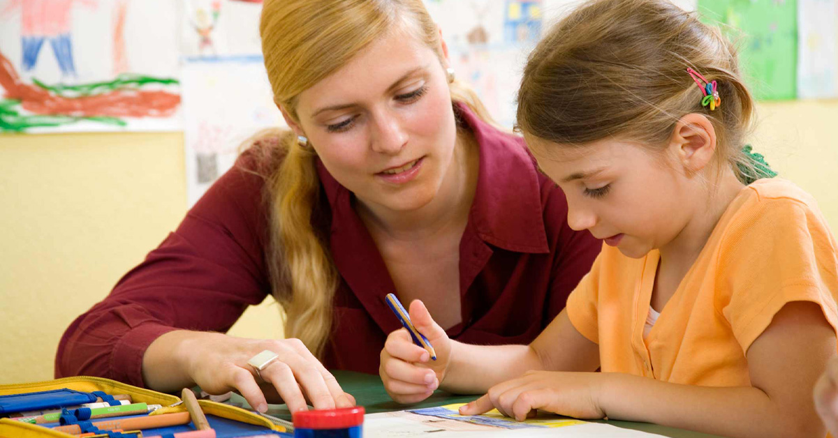 A woman is helping a little girl with her drawing.