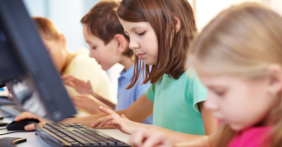 A group of children using computers in front of a desk.