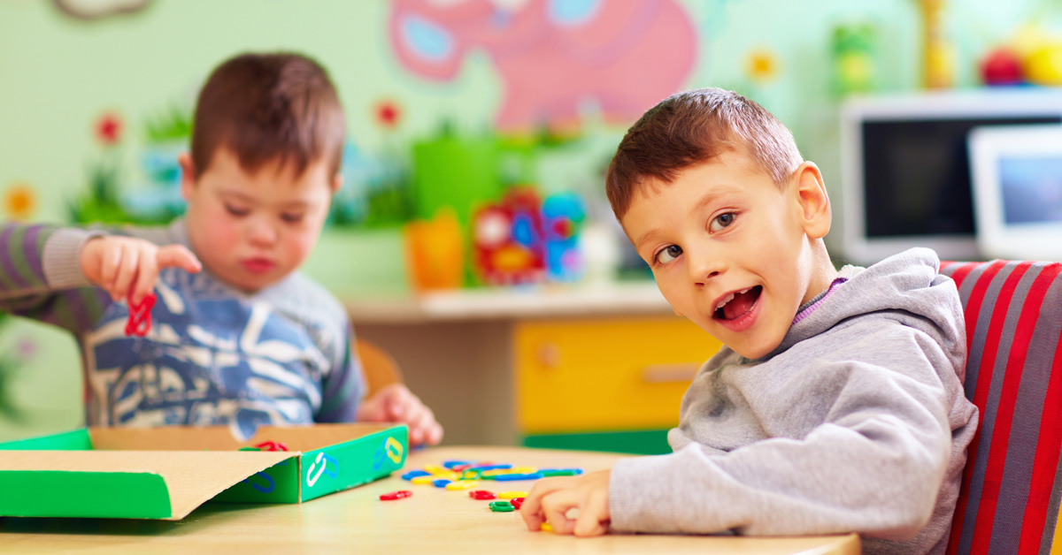 Two boys playing with blocks at a table in a classroom.