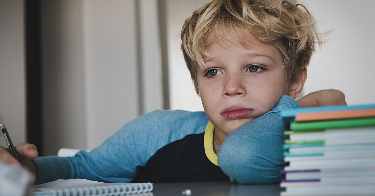 A young boy sitting at a desk with a notebook.