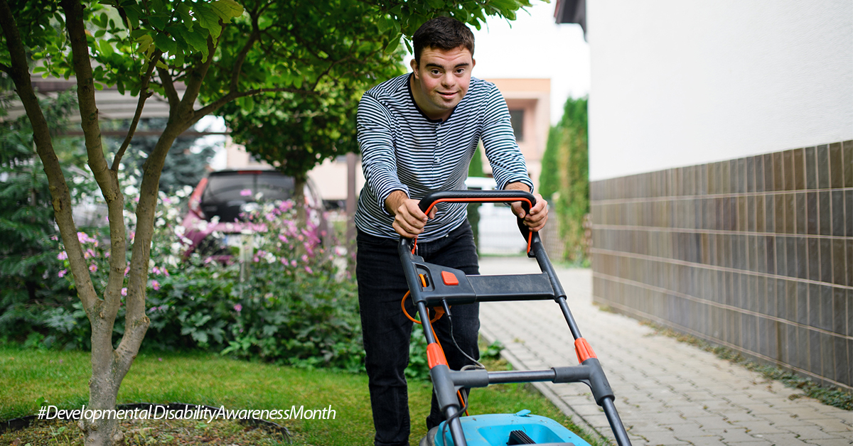 A man pushing a lawn mower in a yard.