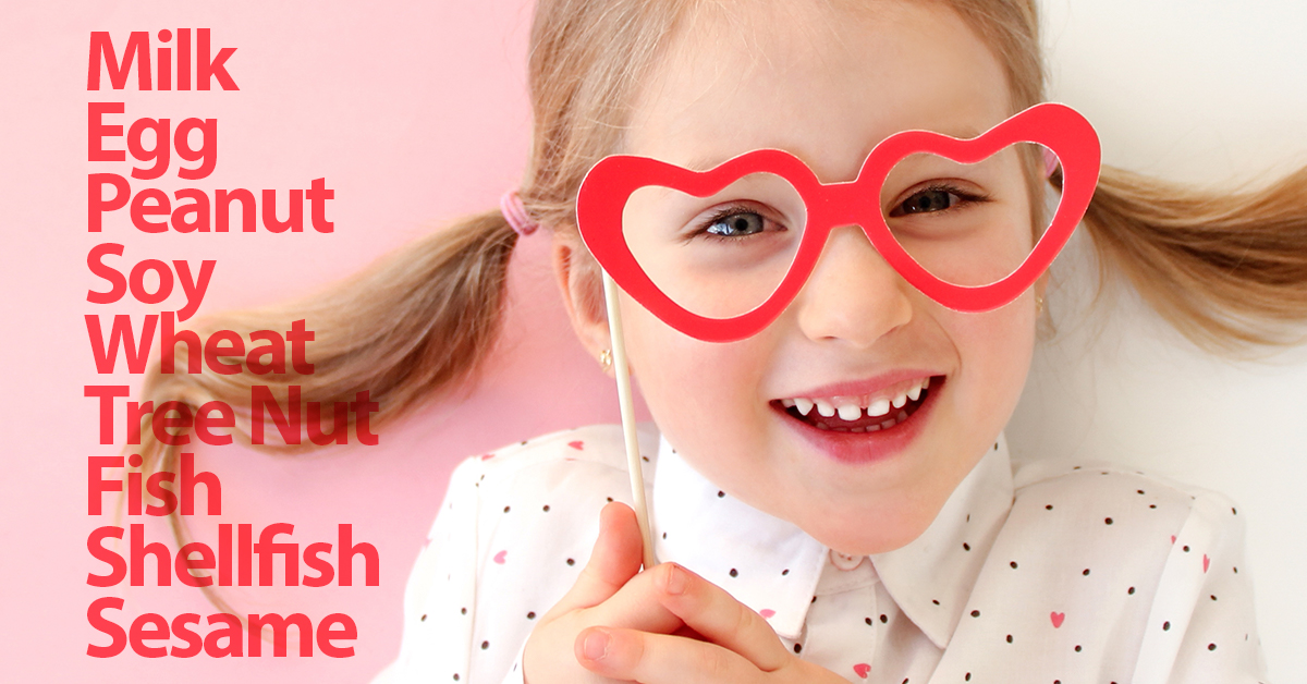 A little girl wearing glasses with the words milk, peanut, egg, soy, wheat, fish, shellfish, sesame.