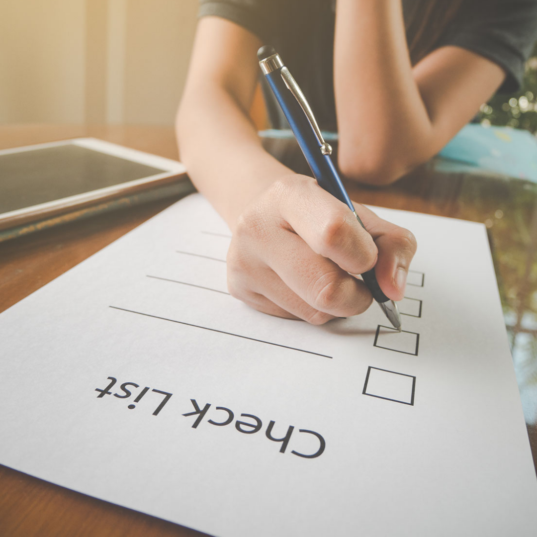 A woman writing a checklist on a piece of paper.