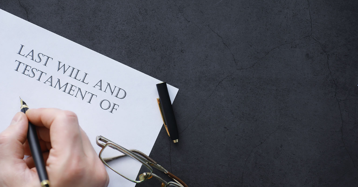 A person signing a document that says last will and testament.