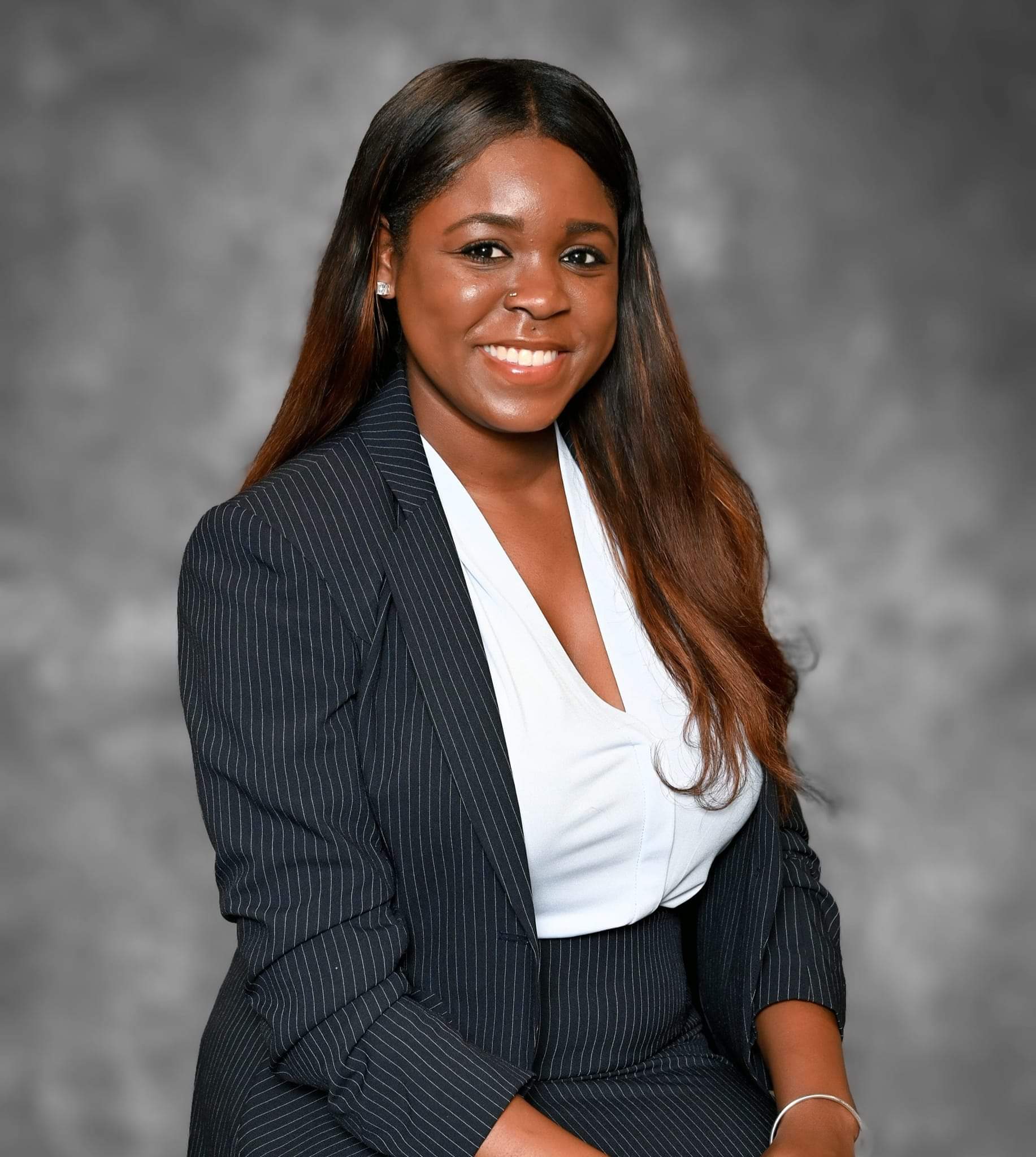 A young woman in a business suit smiling.