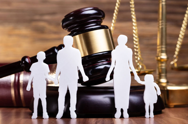 A silhouette of a family and a gavel on a wooden table.